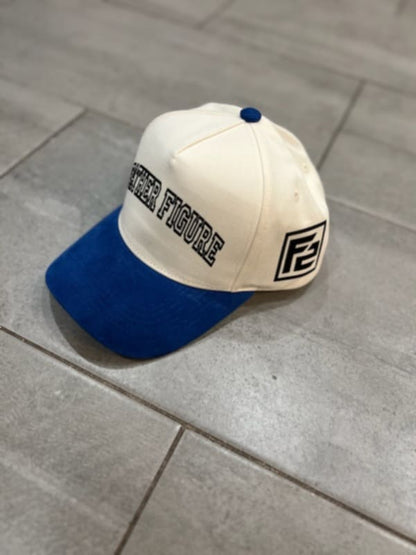 A cream-colored baseball cap with blue corduroy brims and text that reads 'Father Figure' on the front.