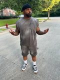 Owner, Reggie George wearing a gray sleeveless shirt and shorts set with black sneakers on a street.