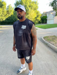 Owner, Reggie George wearing a black sleeveless shirt and shorts with 'Father Figure' text, standing on a street.