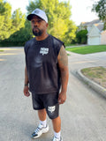 Owner, Reggie George wearing a black sleeveless shirt and shorts with 'Father Figure' text, standing on a street.